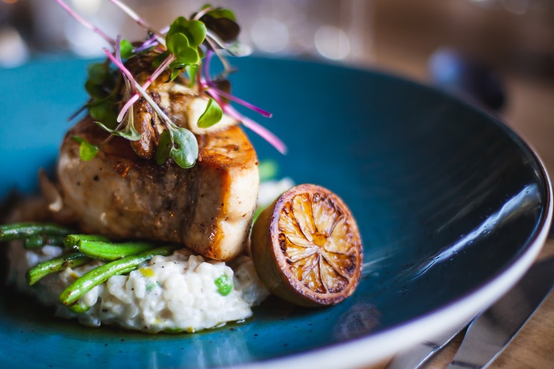 Gourmet meal with fish on risotto served on a blue plate.